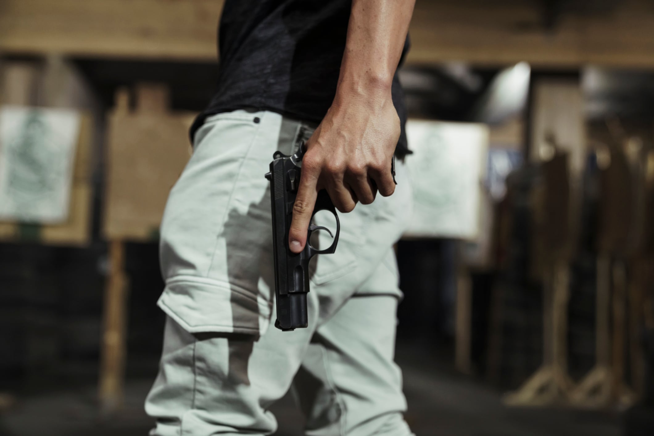 Close-up of man holding a pistol in an indoor shooting range
