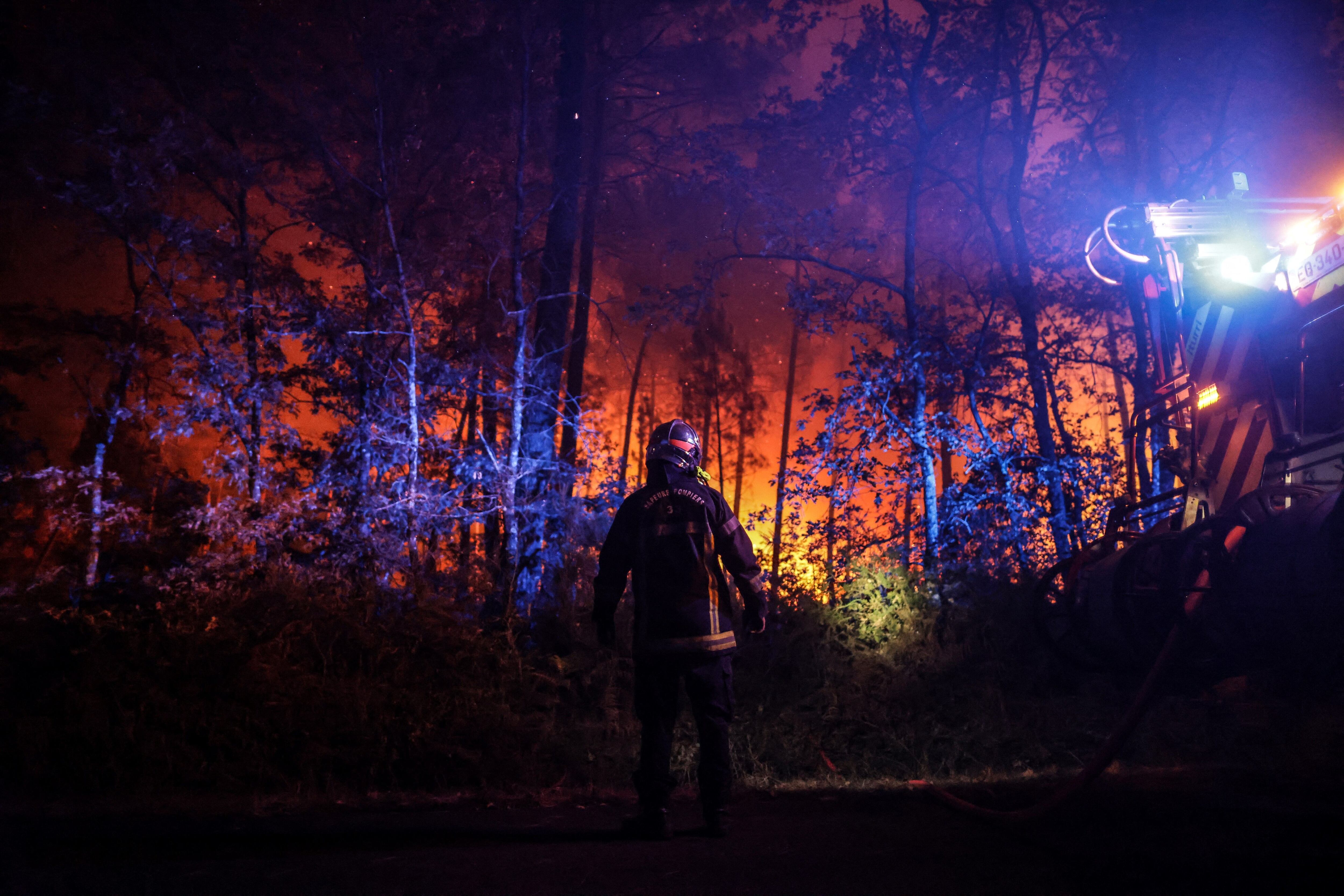 Un bombero junto a su vehículo en un incendio forestal cerca de Belin-Beliet, en el suroeste de Francia, durante la noche del 11 de agosto de 2022. (Photo by THIBAUD MORITZ/AFP via Getty Images)