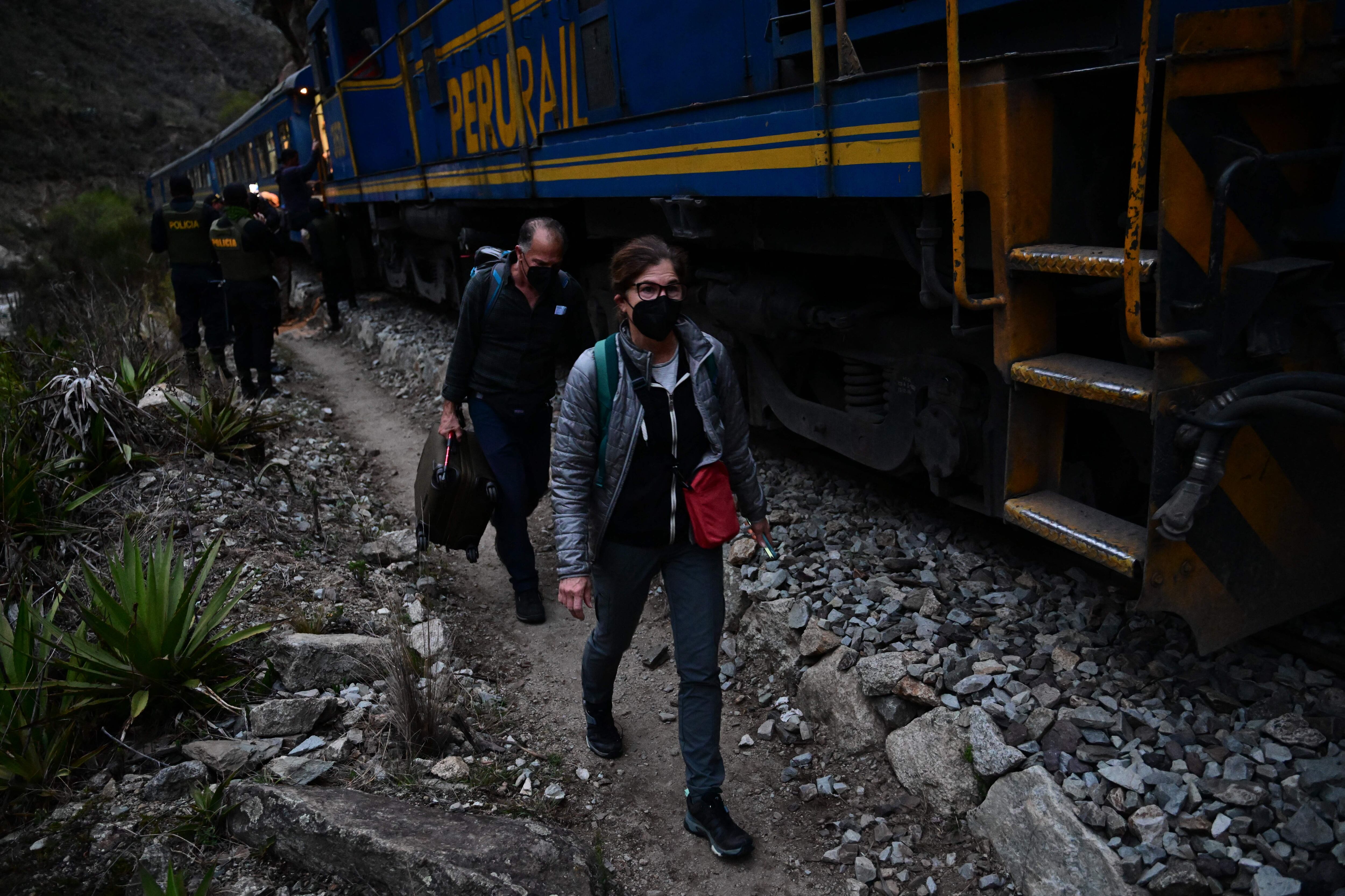 Los turistas varados que visitaban la ciudadela inca de Machu Picchu caminan junto a las vías del tren después de ser evacuados en tren a Ollantaytambo, Perú, el 17 de diciembre de 2022.