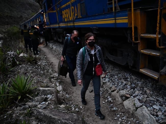 Los turistas varados que visitaban la ciudadela inca de Machu Picchu caminan junto a las vías del tren después de ser evacuados en tren a Ollantaytambo, Perú, el 17 de diciembre de 2022.