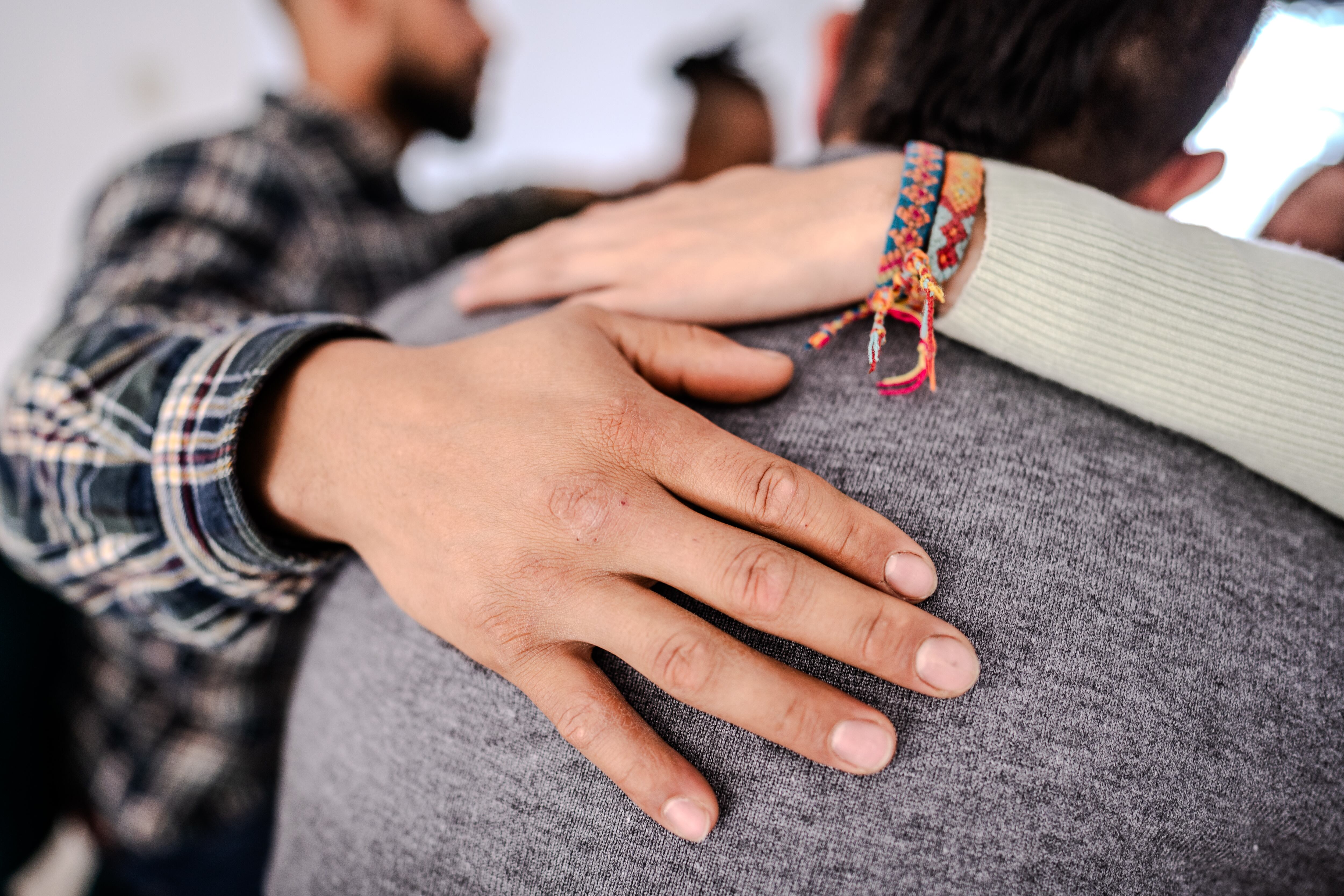 Primer plano de una mano en el hombro consolando a otro paciente durante una sesión de terapia de grupo. Getty Images