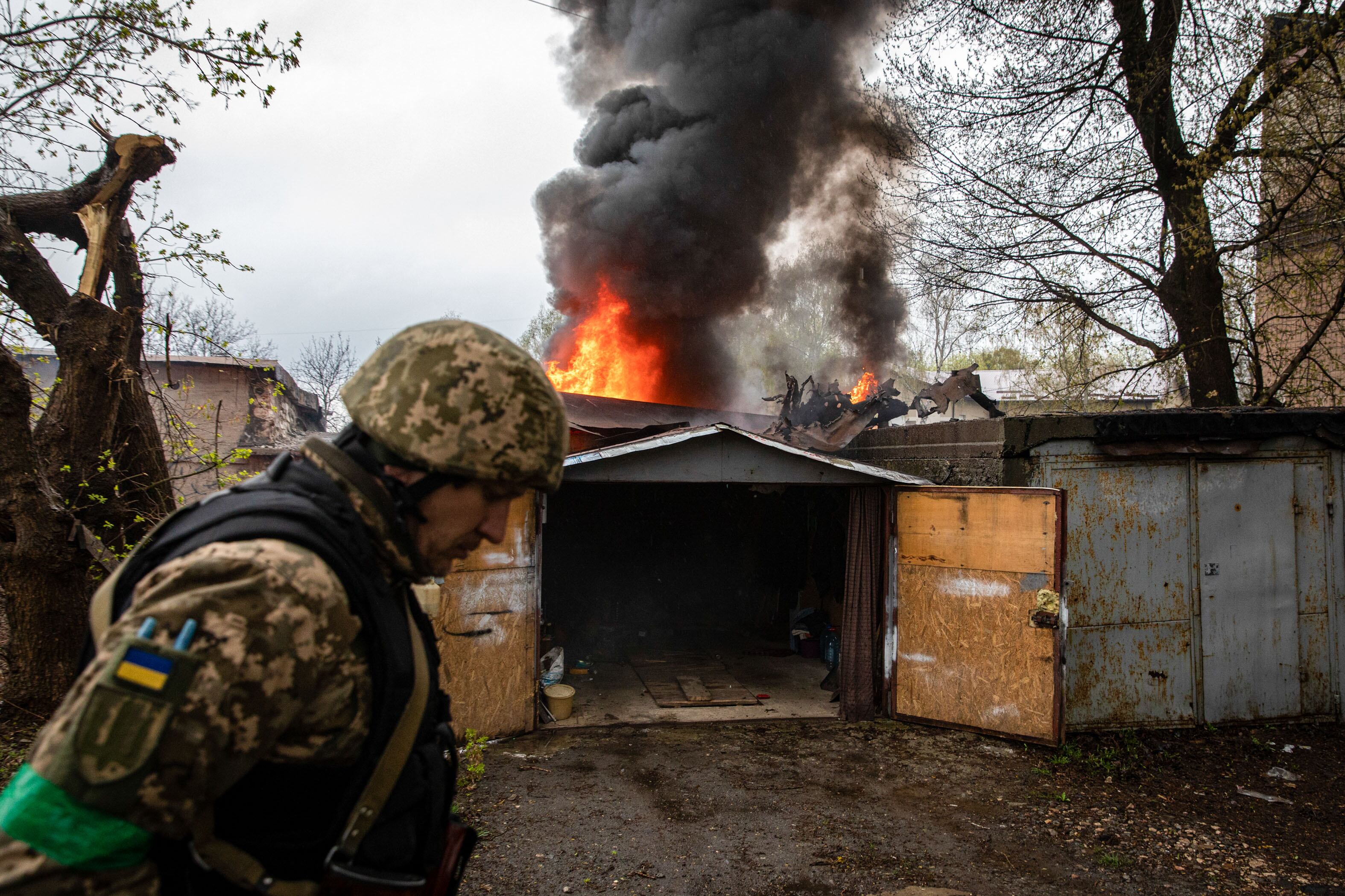 LOSEVO, KHARKIV, UKRAINE - 2022/04/18: A Ukrainian soldier walks in front of a burning garage following a Russian artillery strike in Kharkiv. Following Russia's renewed offensive on the eastern part of Ukraine, Kharkiv, the second biggest city in Ukraine, is now under constant threat of Russian bombardment and airstrikes. (Photo by Alex Chan Tsz Yuk/SOPA Images/LightRocket via Getty Images)