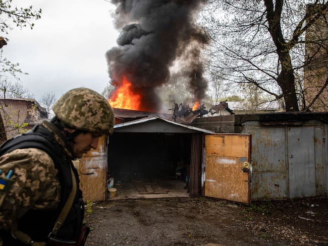 LOSEVO, KHARKIV, UKRAINE - 2022/04/18: A Ukrainian soldier walks in front of a burning garage following a Russian artillery strike in Kharkiv. Following Russia&#039;s renewed offensive on the eastern part of Ukraine, Kharkiv, the second biggest city in Ukraine, is now under constant threat of Russian bombardment and airstrikes. (Photo by Alex Chan Tsz Yuk/SOPA Images/LightRocket via Getty Images)