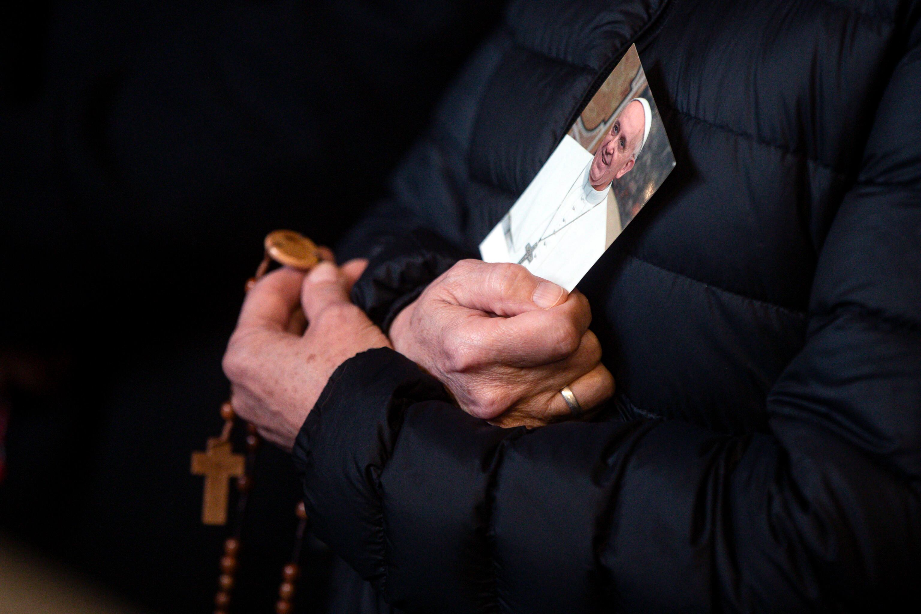 CIUDAD DEL VATICANO (Italia), 25/02/2025.- Una persona sostiene una imagen del papa Francisco mientras fieles asisten a la Plaza de San Pedro a una oración del Rosario por la salud del pontífice, que permanece hospitalizado en el Hospital Agostino Gemelli.