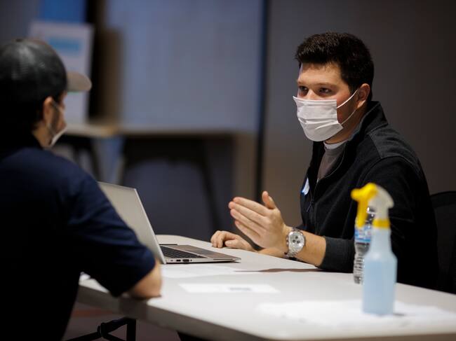 SPRING HILL, TN - NOVEMBER 16: An applicant (left) is walked through their job offer by a General Motors employee during a job fair on November 16, 2021 in Spring Hill, Tennessee. General Motors is looking to hire 120 temporary employees to help add another shift to the engine manufacturing line at this facility. (Photo by Brett Carlsen/Getty Images)