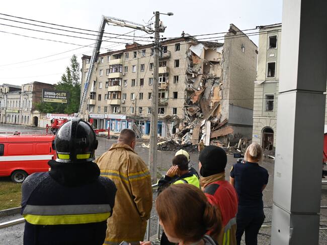 Local residents watch Ukrainian rescuers working outside a building partially destroyed after a Russian missile strike in Kharkiv on July 11, 2022, amid Russia&#039;s military invasion launched on Ukraine. (Photo by SERGEY BOBOK / AFP) (Photo by SERGEY BOBOK/AFP via Getty Images)