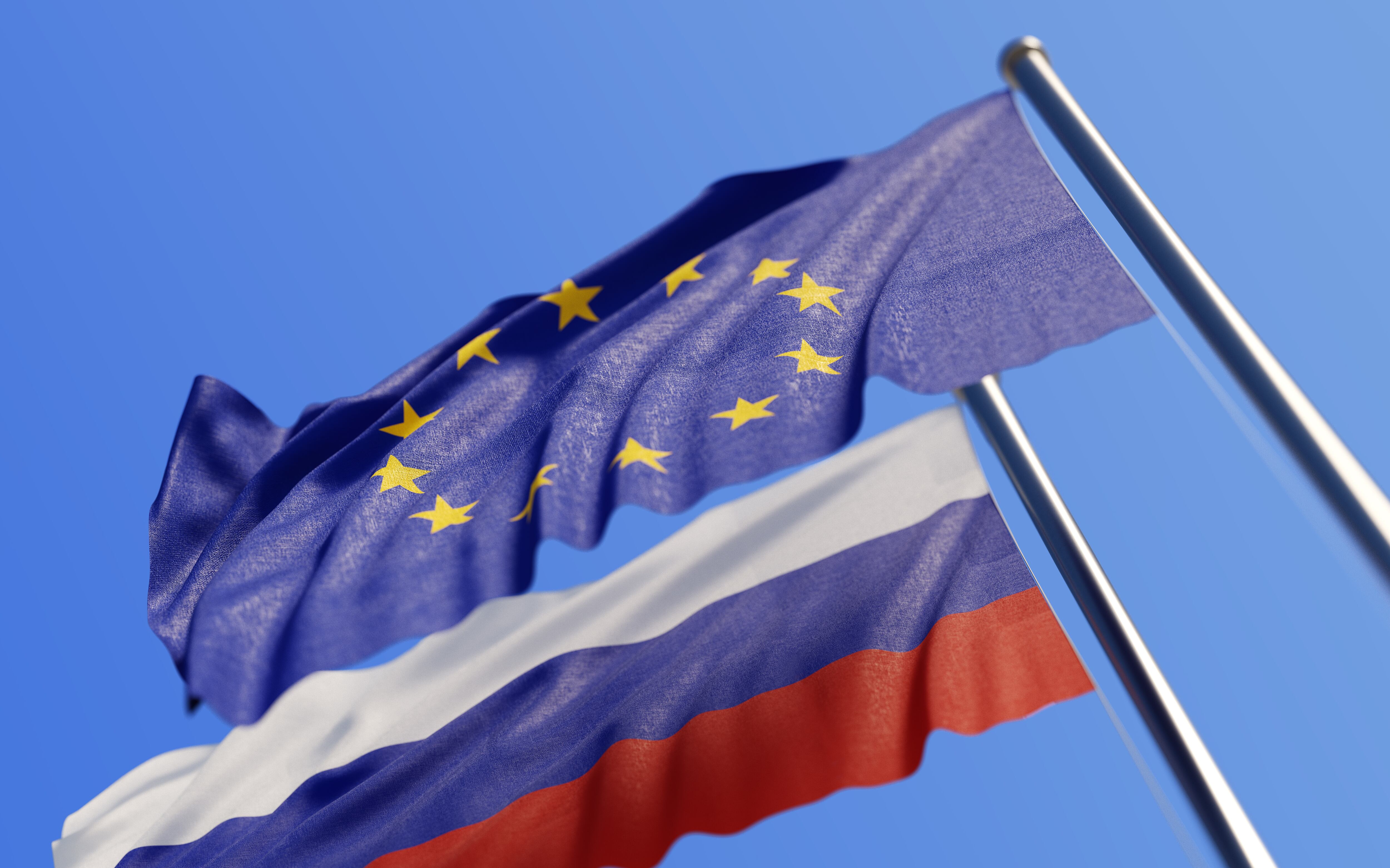 High quality 3d render of European Union and Russian flags waving with wind on a blue sky. Low angle view with copy space and selective focus.