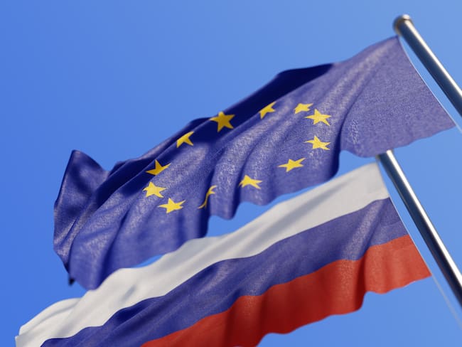 High quality 3d render of European Union and Russian flags waving with wind on a blue sky. Low angle view with copy space and selective focus.