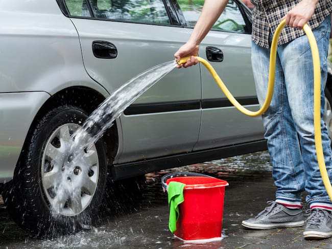 Lavar vehículos en vía pública, imagen de referencia. Foto: Getty Images.