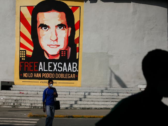 People walk past graffiti in favor of the release of Colombian businessman Alex Saab, amidst the Coronavirus pandemic, on the west side of the city in Caracas, Venezuela on September 8, 2021. (Photo by Javier Campos/NurPhoto via Getty Images)