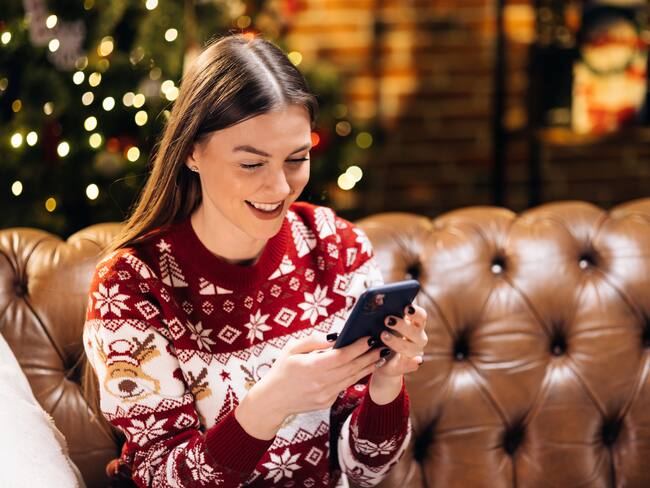 Mujer durante la Navidad chateando por su celular. (Foto vía Getty Images)