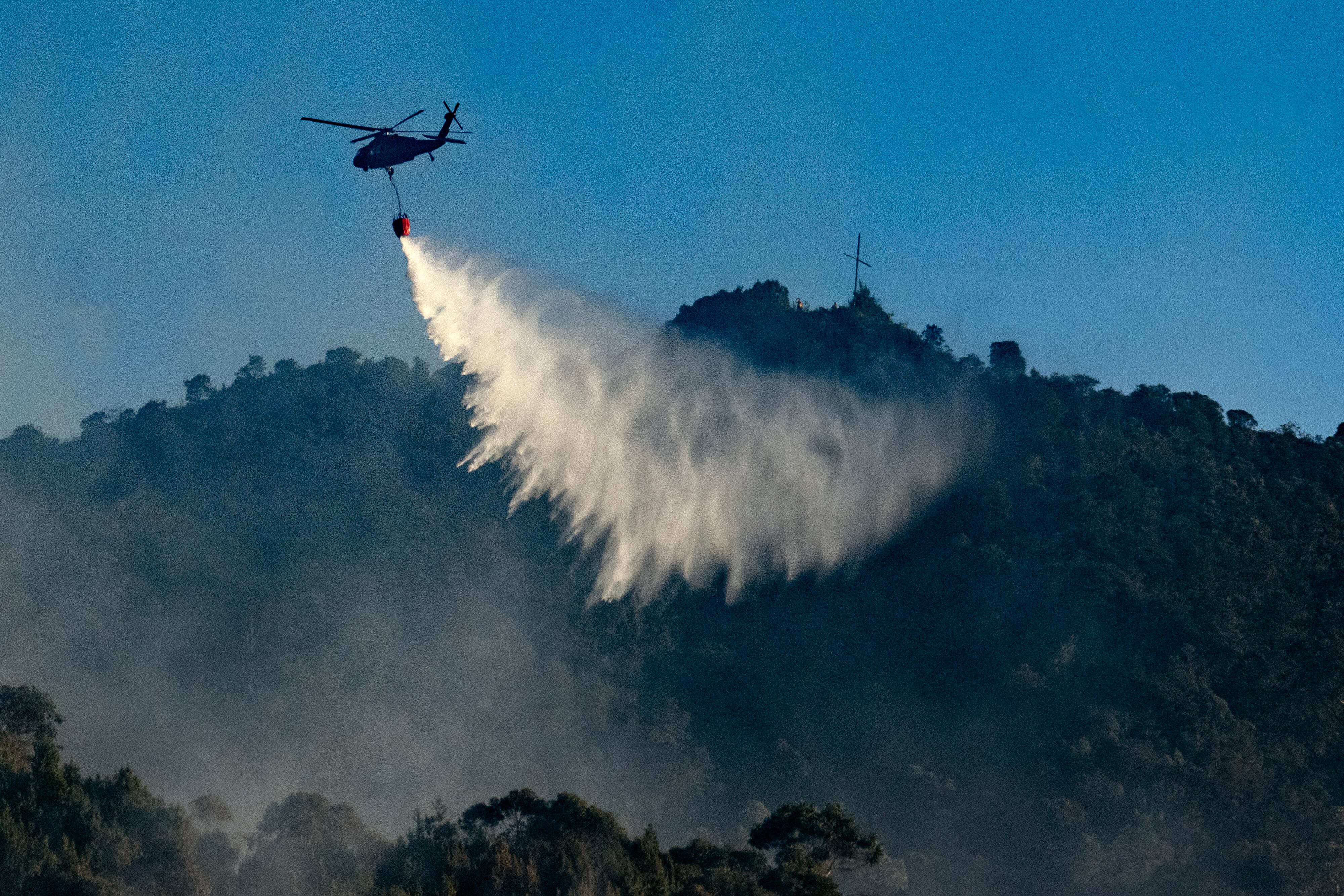 Un helicóptero de las Fuerzas Armadas arroja agua para apagar un incendio forestal en Bogotá el 23 de enero de 2024.