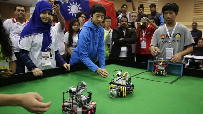 Dos adolescentes taiwaneses observan a sus robots jugar al fútbol en la Olimpíada Mundial de Robots en Nueva Delhi, India. Foto: Associated Press - AP - Tsering Topgyal