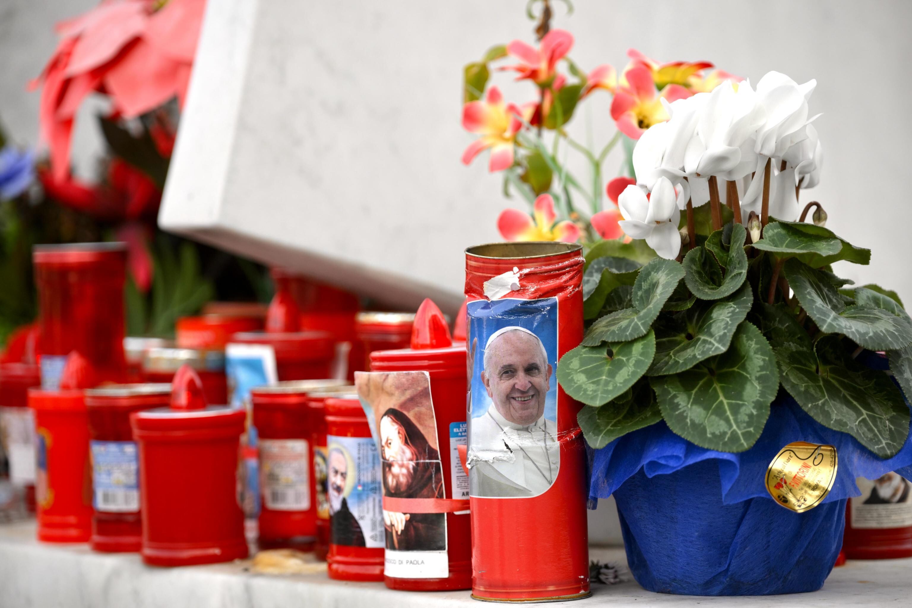 Roma (Italia), 18/02/2025.- Flores y velas son depositadas a los pies de una estatua del Papa Juan Pablo II fuera del Hospital Universitario Gemelli, donde el Papa Francisco está hospitalizado por pruebas y tratamiento de bronquitis.