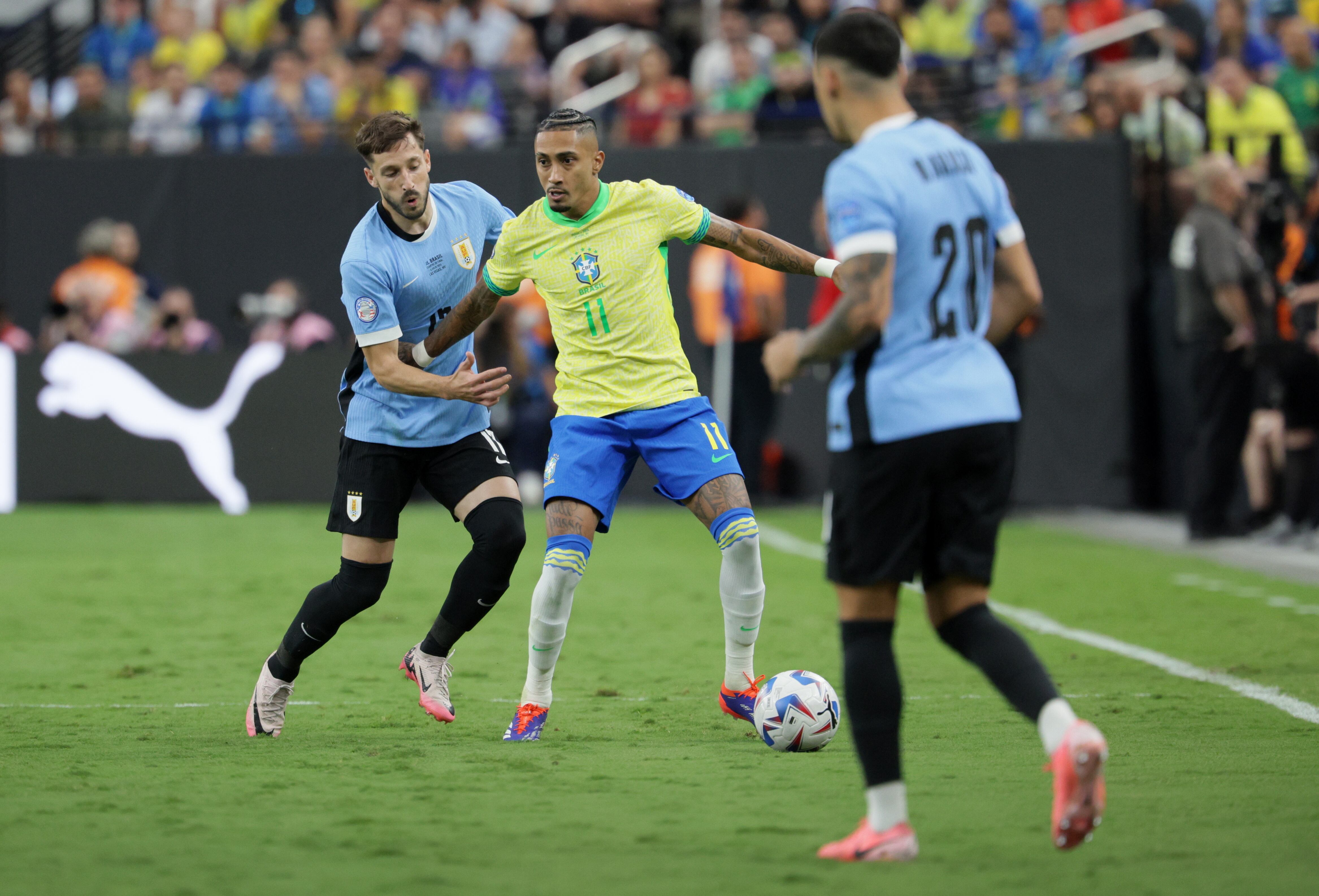 Las Vegas (United States), 07/07/2024.- Raphinha Dias of Brazil (C) in action against Matias Vina of Uruguay (L) and Maximiliano Araujo of Uruguay (R) during the CONMEBOL Copa America 2024 Quarter-finals match between Uruguay and Brazil, in Las Vegas, Nevada, USA, 06 July 2024. (Brasil) EFE/EPA/ALLISON DINNER