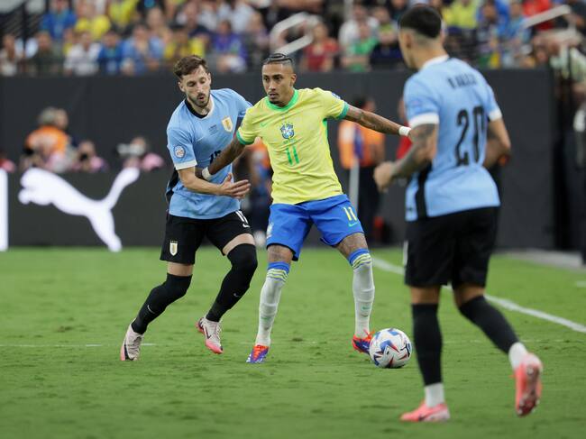 Las Vegas (United States), 07/07/2024.- Raphinha Dias of Brazil (C) in action against Matias Vina of Uruguay (L) and Maximiliano Araujo of Uruguay (R) during the CONMEBOL Copa America 2024 Quarter-finals match between Uruguay and Brazil, in Las Vegas, Nevada, USA, 06 July 2024. (Brasil) EFE/EPA/ALLISON DINNER
