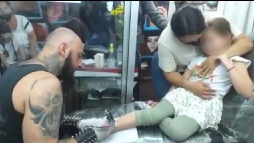 Niña fue llevada por su madre a hacerse un tatuaje. Foto: Captura de video.
