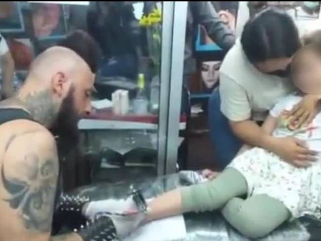 Niña fue llevada por su madre a hacerse un tatuaje. Foto: Captura de video.