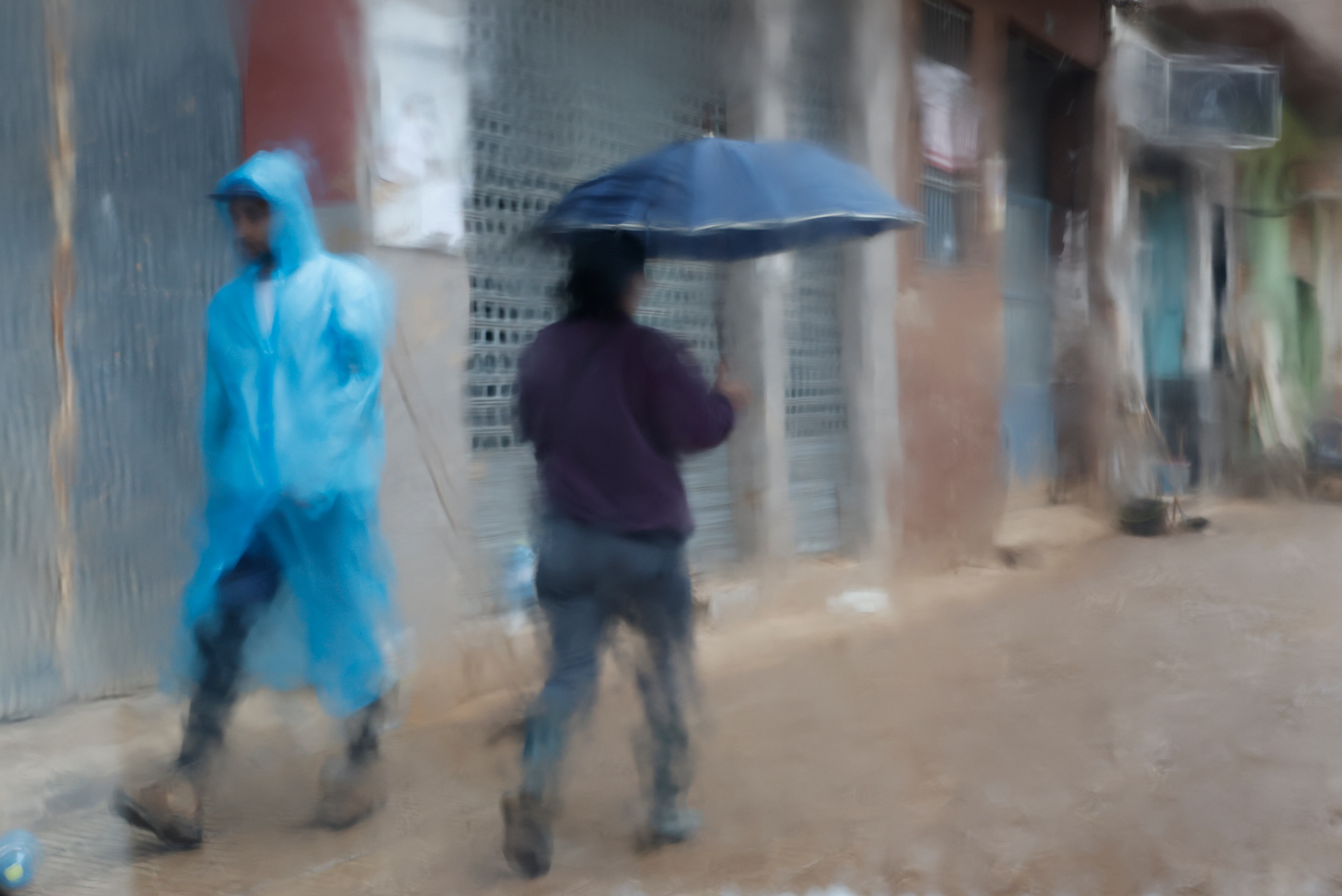 PAIPORTA (VALÈNCIA), 13/11/2024.- Fotografía tomada tras un cristal de dos personas que caminan protegida para la lluvia por Paiporta (Valencia) este miércoles. El Ayuntamiento valenciano de Paiporta ha pedido a los voluntarios que acuden cada día a ayudar a paliar los efectos de la dana del pasado 29 de octubre que, por seguridad, eviten entrar en los municipios afectados por las inundaciones y que se encuentran en alerta naranja por lluvias este miércoles. EFE/Jorge Zapata