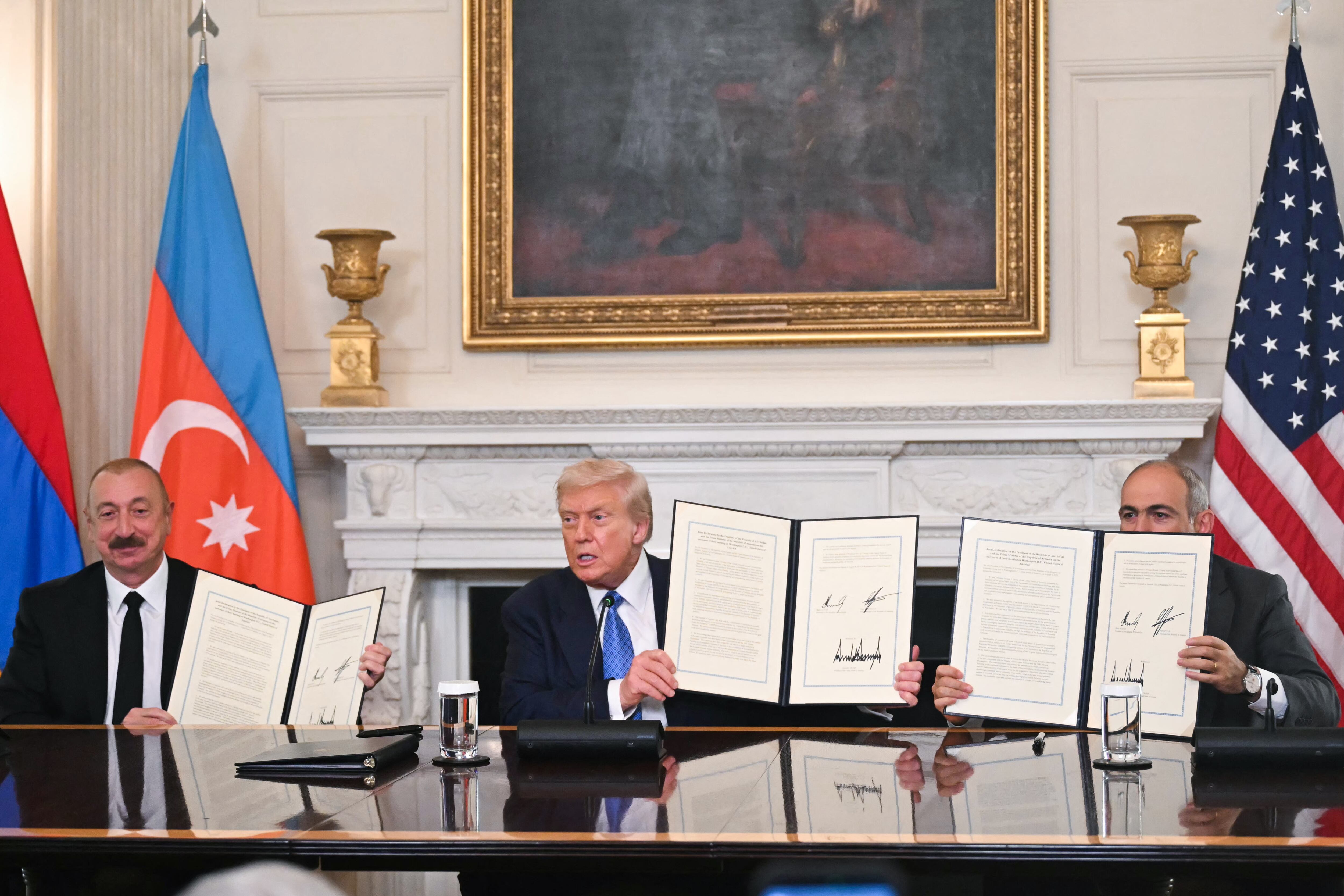 El presidente estadounidense Donald Trump, el presidente azerbaiyano Ilham Aliyev y el primer ministro armenio Nikol Pashinyan muestran el acuerdo que firmaron en el Comedor de Estado de la Casa Blanca en Washington D.C., el 8 de agosto de 2025. (Foto de ANDREW CABALLERO-REYNOLDS/AFP vía Getty Images)