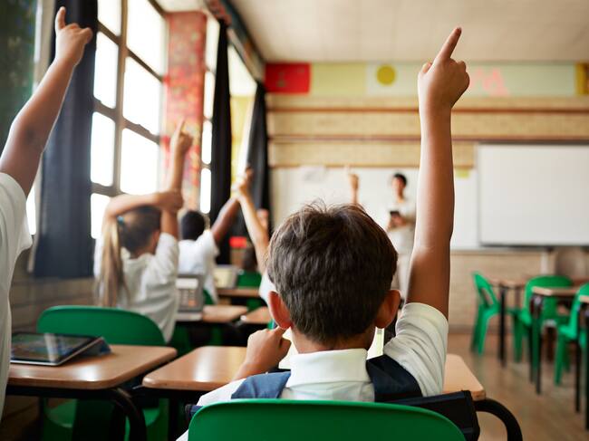 School children in uniforms in class with tablets