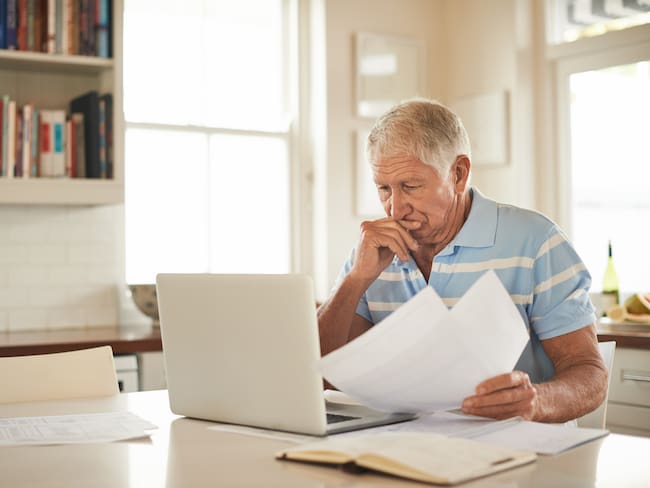 Hombre preocupado revisando recibos públicos (GettyImages)