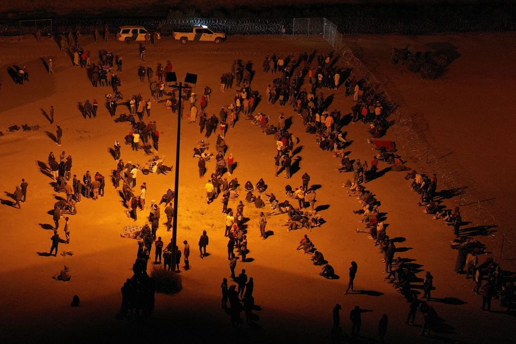 Migrants wait at night along the border wall to surrender to US Customs and Border Protection (CBP) Border Patrol agents for immigration and asylum claim processing before the expiration of Title 42 upon crossing the Rio Grande river from Ciudad Juarez into the United States on the US-Mexico border in El Paso, Texas on May 11, 2023. Covid-era rules that have prevented hundreds of thousands of people from claiming asylum at the southern US border expired early on May 11, 2023, creating uncertainty for migrants and setting off a political firestorm.The government of President Joe Biden says it is trying to balance a humane system of offering refuge to those in need with one that will prevent an uncontrollable spike in arrivals. (Photo by Patrick T. Fallon / AFP) (Photo by PATRICK T. FALLON/AFP via Getty Images)