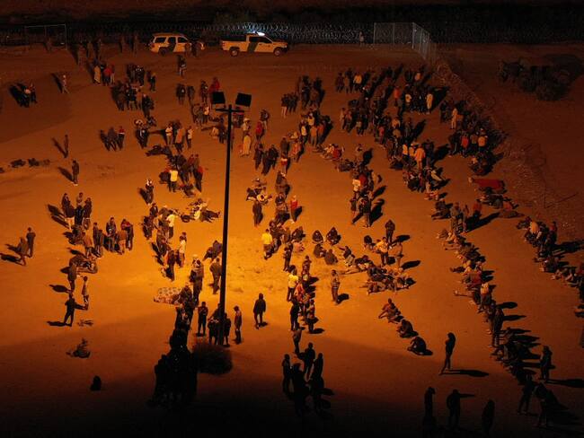 Migrants wait at night along the border wall to surrender to US Customs and Border Protection (CBP) Border Patrol agents for immigration and asylum claim processing before the expiration of Title 42 upon crossing the Rio Grande river from Ciudad Juarez into the United States on the US-Mexico border in El Paso, Texas on May 11, 2023. Covid-era rules that have prevented hundreds of thousands of people from claiming asylum at the southern US border expired early on May 11, 2023, creating uncertainty for migrants and setting off a political firestorm.The government of President Joe Biden says it is trying to balance a humane system of offering refuge to those in need with one that will prevent an uncontrollable spike in arrivals. (Photo by Patrick T. Fallon / AFP) (Photo by PATRICK T. FALLON/AFP via Getty Images)