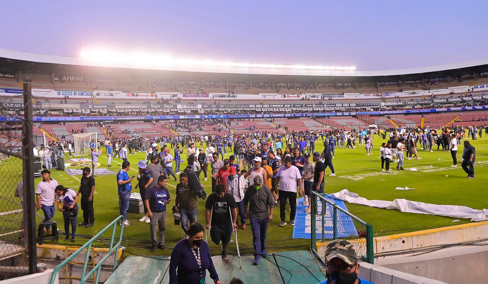Aficionados del Querétaro y del Atlas se retiran tras un conato de pelea que terminó invadiendo la cancha, durante un juego correspondiente a la jornada 9 del Torneo Clausura 2022 de la Liga MX del fútbol mexicano en el estadio Corregidora de la ciudad de Querétaro (México).