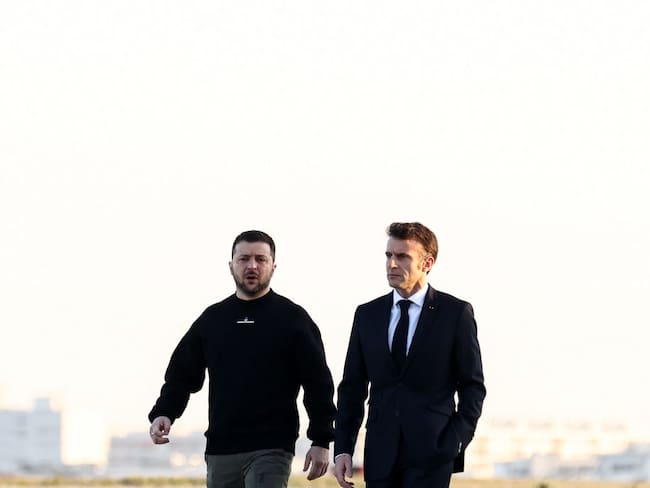 France's President Emmanuel Macron (R) and Ukrainian President Volodymyr Zelensky walk on the tarmac of Velizy-Villacoublay airbase as they prepare to board a flight together, en route to Brussels for a summit at EU parliament, on February 9, 2023. - Ukraine's President is set to attend an EU summit in Brussels on February 9, 2023, as the guest of honour where he will press allies to deliver fighter jets "as soon as possible" in the war against Russia. (Photo by MOHAMMED BADRA / POOL / AFP) (Photo by MOHAMMED BADRA/POOL/AFP via Getty Images)