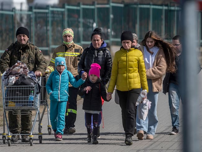 A Polish serviceman (L) helps Ukrainian refugees to cross the Ukrainian border with Poland at the Medyka border crossing, southeastern Poland, on March 27, 2022, following Russia&#039;s invasion of Ukraine about one month ago. (Photo by Angelos Tzortzinis / AFP) (Photo by ANGELOS TZORTZINIS/AFP via Getty Images)