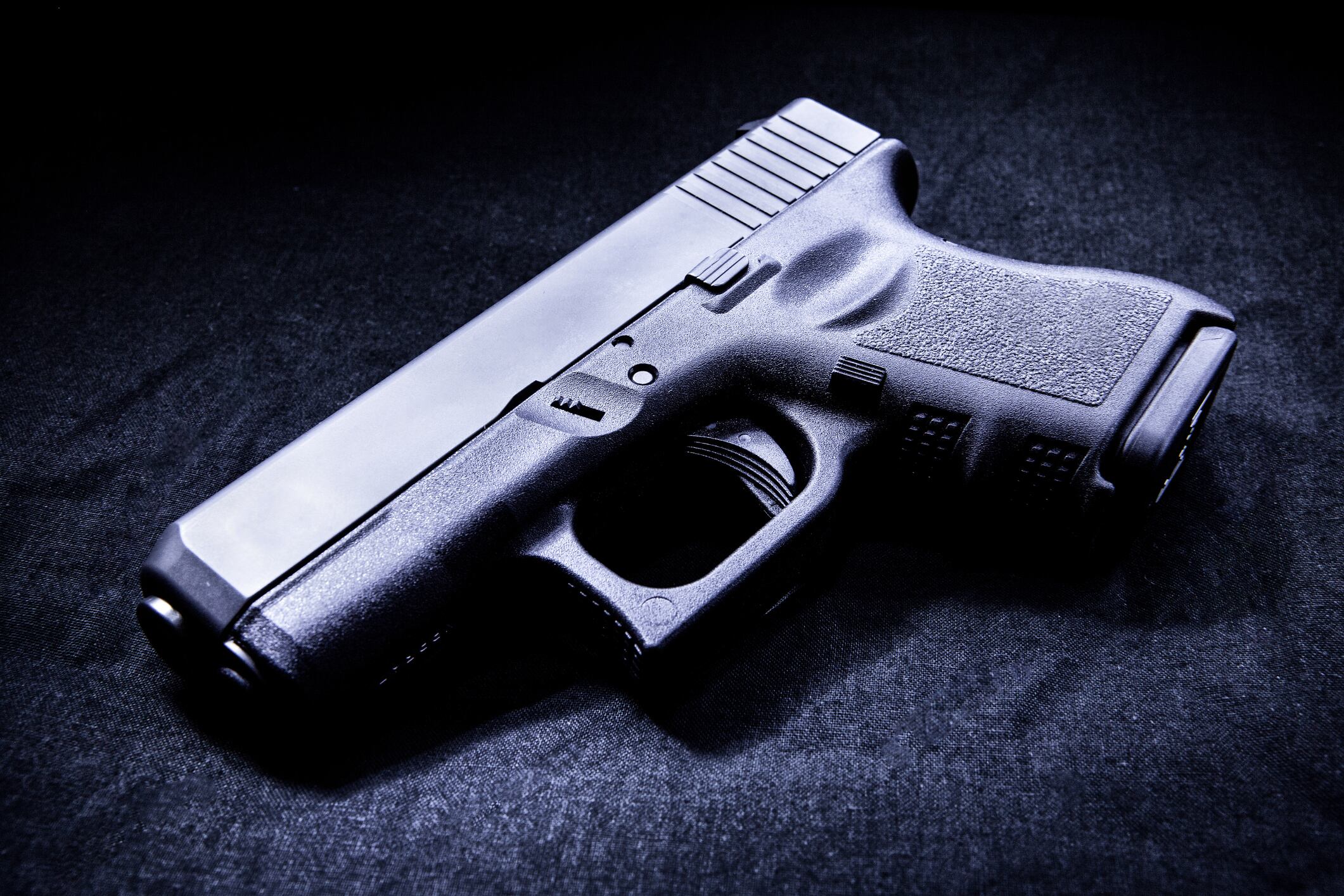 Handgun in a dark room lit by a single light source