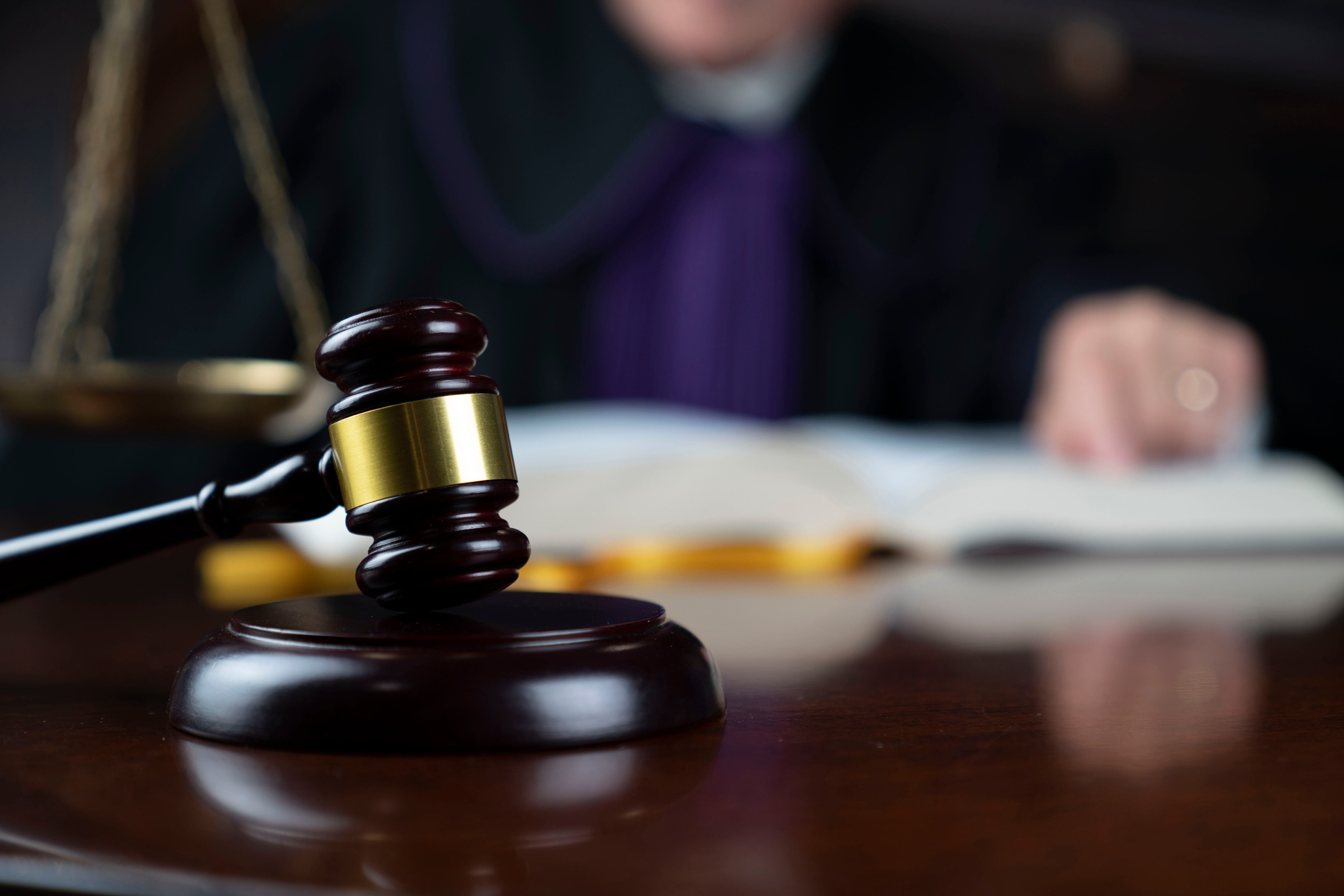 Judge looking through legal code with the wooden gavel in his hand.