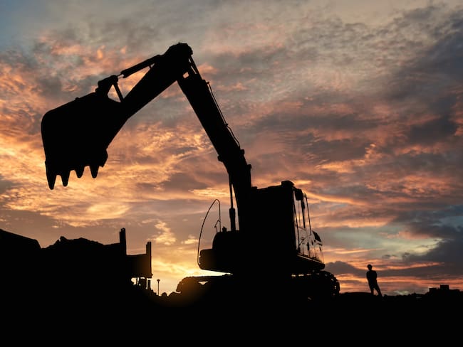 Various pieces of construction equipment are sihouetted by the sunset
