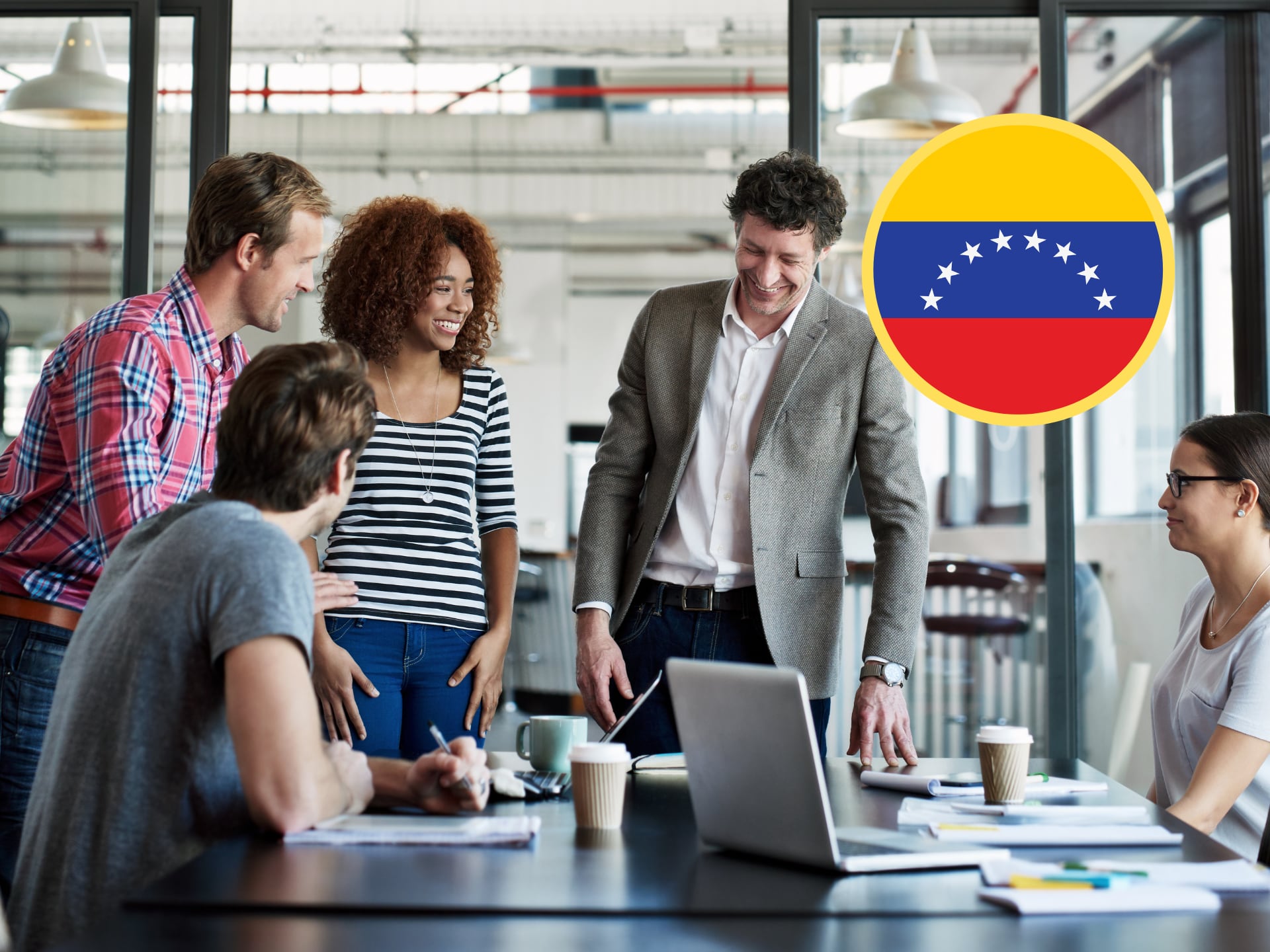 Trabajadores en una oficina, junto a la bandera de Venezuela (GettyImages)