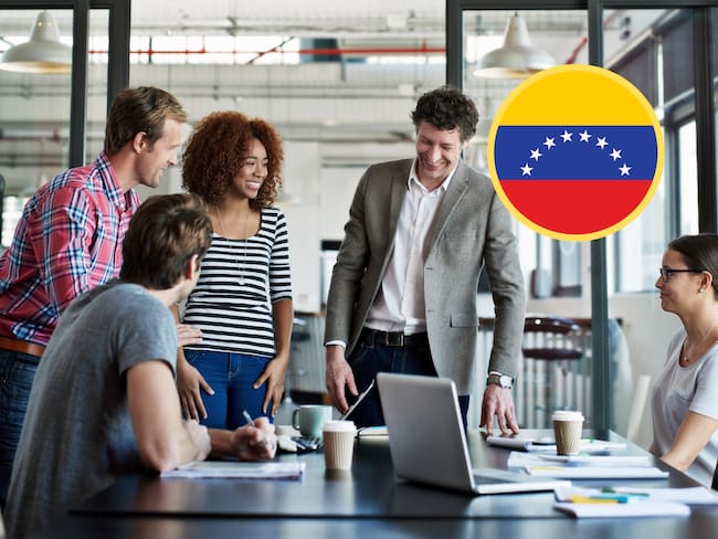 Trabajadores en una oficina, junto a la bandera de Venezuela (GettyImages)