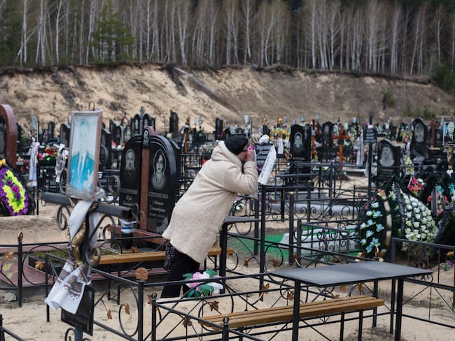 BUCHA, UKRAINE - APRIL 18: Olena kisses the cross on the grave of her father on April 18, 2022 at the cemetery in Bucha, Ukraine. The Russian retreat from Ukrainian towns and cities has revealed scores of civilian deaths and the full extent of devastation from Russia's attempt to dominate the country. (Photo by Anastasia Vlasova/Getty Images)
