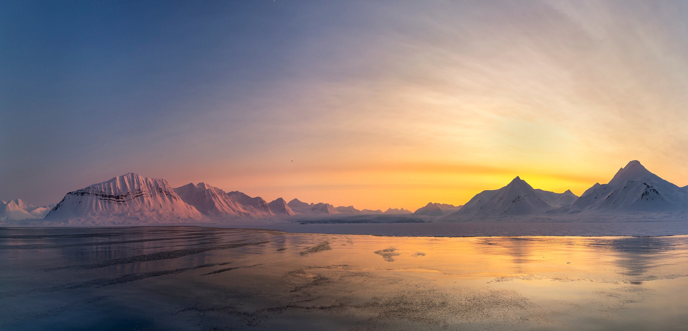 Vista panorámica de unas montañas nevadas con el 'Sol de medianoche' (Foto vía GettyImages)
