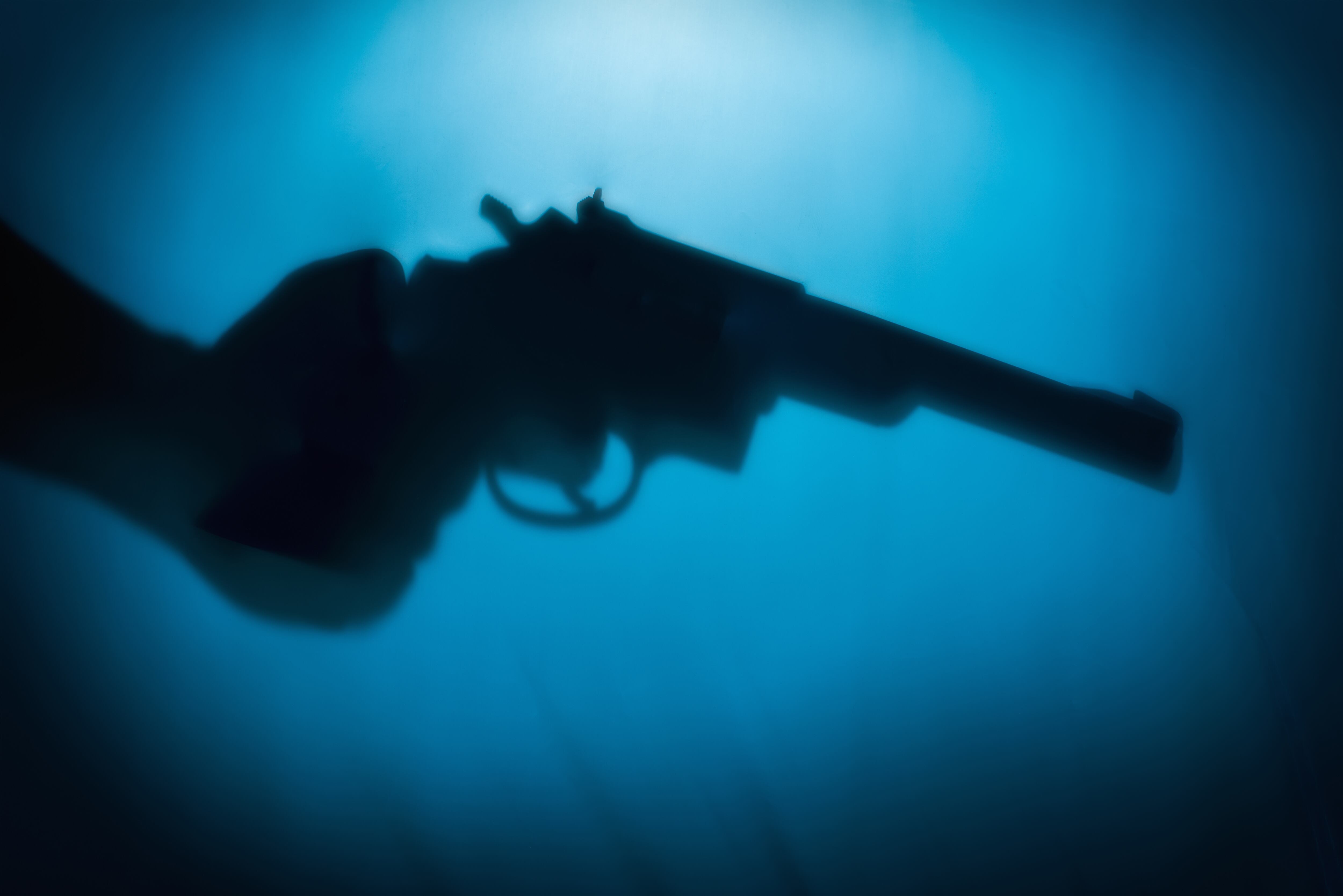 Silhouette of man's hand holding a pistol