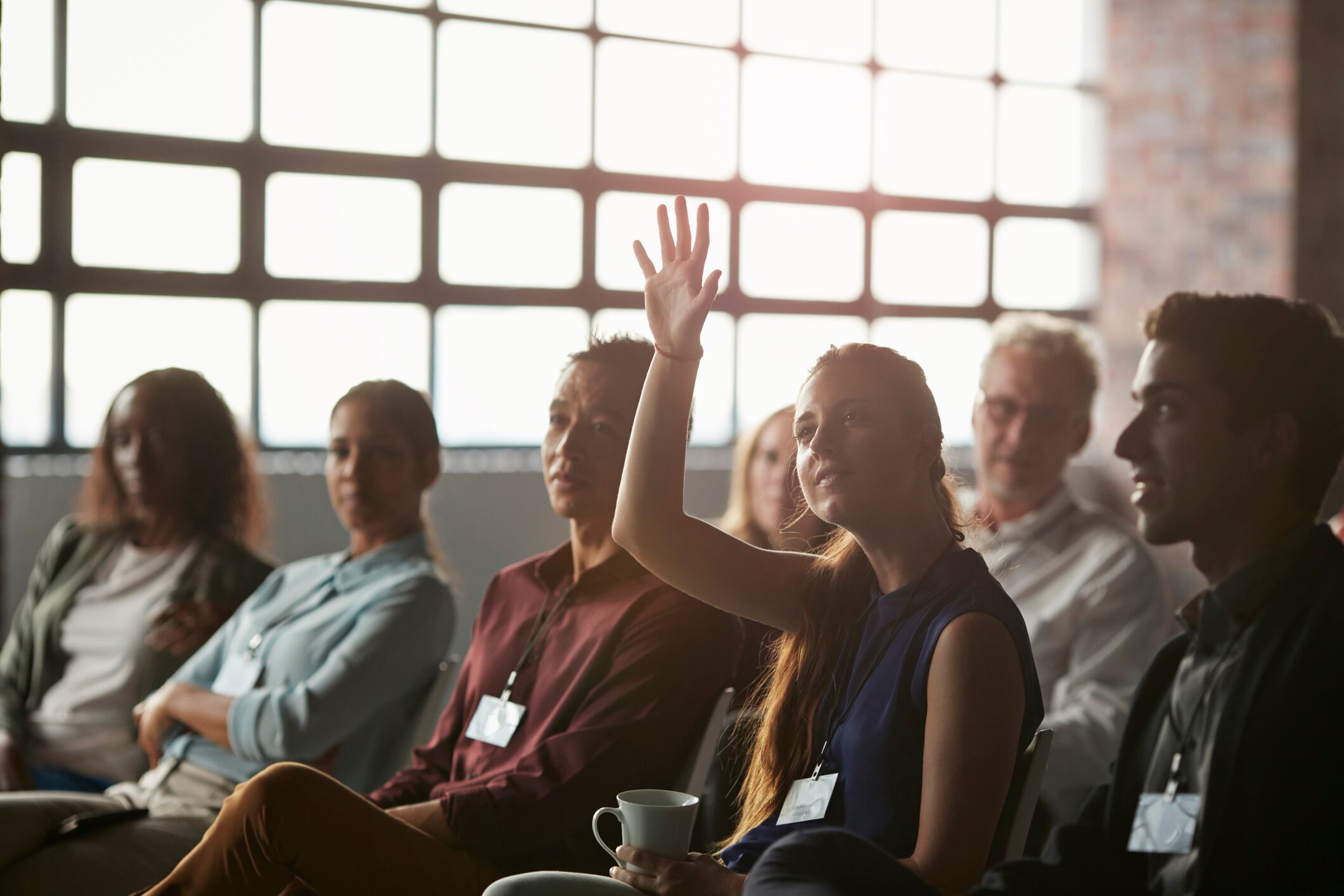 Businesswoman with raised hand at convention in New York style auditorium