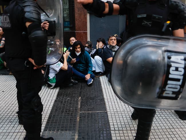 AME8880. BUENOS AIRES (ARGENTINA), 12/03/2025.- Miembros de la policía argentina vigilan a manifestantes este miércoles, en Buenos Aires (Argentina). Las fuerzas de seguridad argentinas cargaron contra los manifestantes al inicio de la marcha convocada por los jubilados, a la que se sumaron aficionados del fútbol, sindicatos y agrupaciones progresistas. EFE/ Juan Ignacio Roncoroni