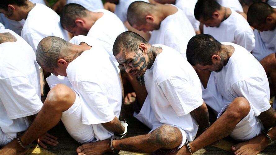 En Zacatecoluca, El Salvador, miembros de la Mara Salvatrucha 13, la pandilla más grande de América Latina, esperan sentados en fila a ser escoltados hasta la prisión de máxima seguridad conocida localmente como "Zacatraz".. Foto: BBC Mundo