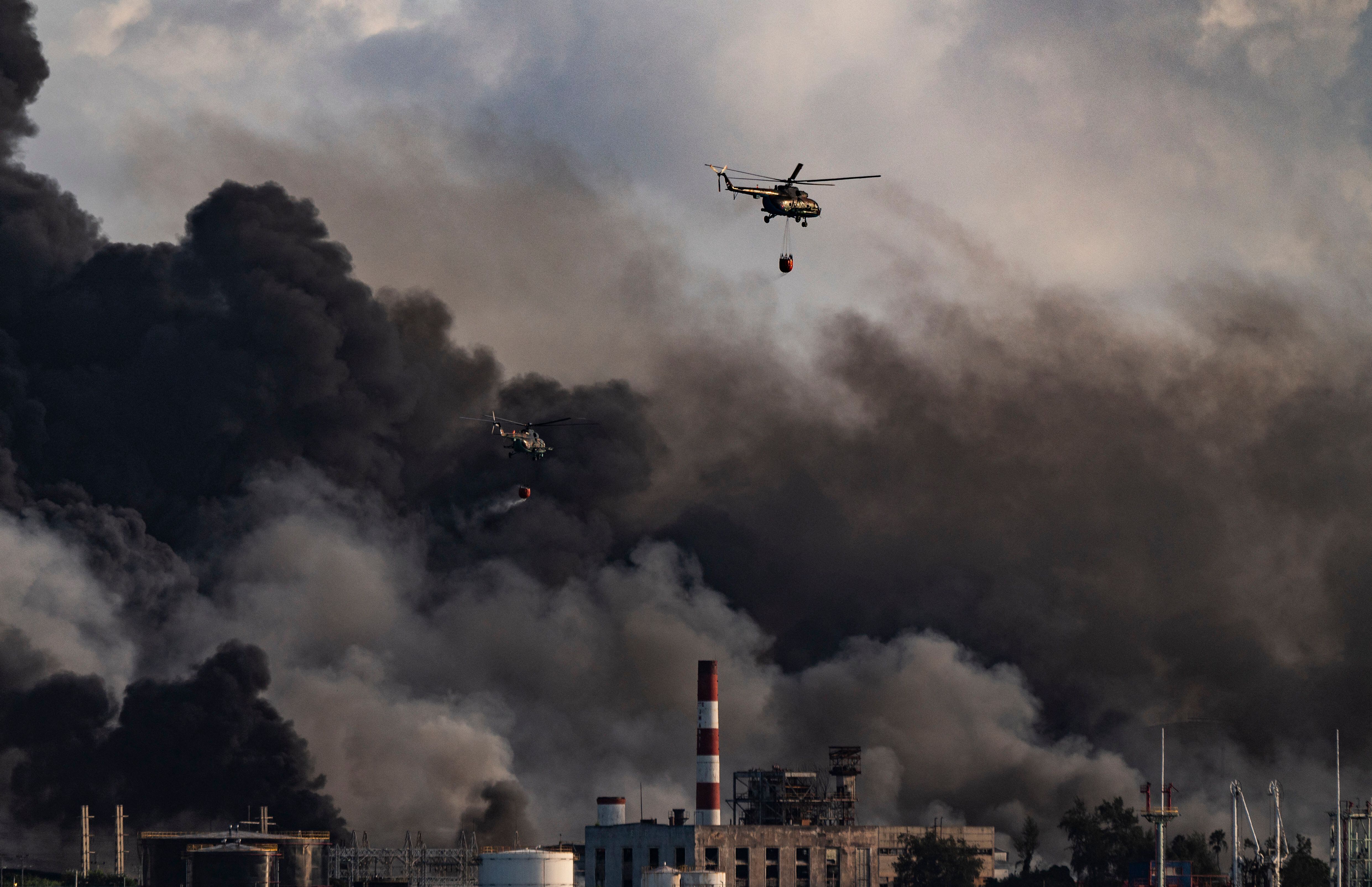 Un helicóptero de bomberos arroja agua sobre un incendio masivo en un depósito de combustible en Matanzas, Cuba, el 8 de agosto de 2022. (Photo by YAMIL LAGE / AFP) (Photo by YAMIL LAGE/AFP via Getty Images)