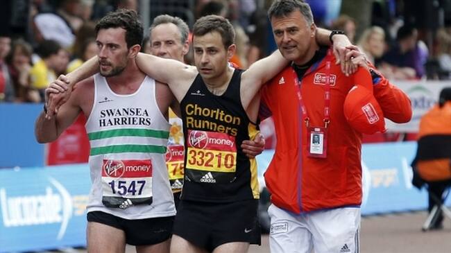 Matthew Rees ayuda a David Wyeth, junto a un responsable de la organización, a cruzar la meta en la maratón de Londres. Foto: Getty Images