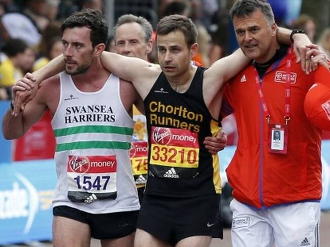 Matthew Rees ayuda a David Wyeth, junto a un responsable de la organización, a cruzar la meta en la maratón de Londres. Foto: Getty Images