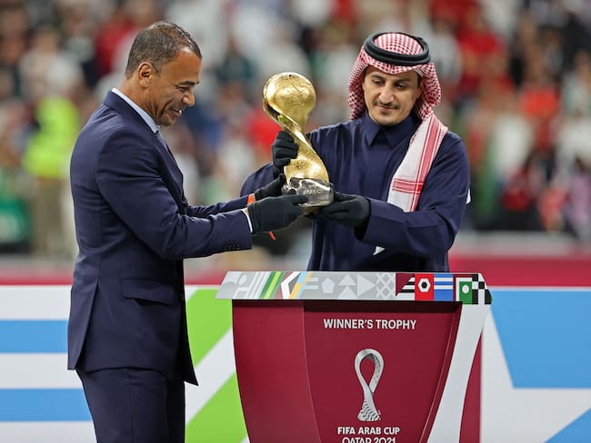 Former Saudi Arabian international Nawaf al-Temyat (R) and former Brazilian world cup winner Cafu carry the trophy at the end of the FIFA Arab Cup 2021 final football match between Tunisia and Algeria at the Al-Bayt stadium in the Qatari city of Al-Khor on December 18, 2021. (Photo by KARIM JAAFAR / AFP) (Photo by KARIM JAAFAR/AFP via Getty Images)
