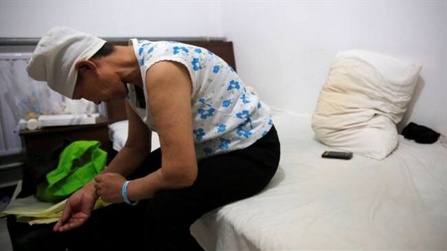 Refugiada del cáncer. Se llama Huang y viajó cientos de kilómetros en busca de un tratamiento que no existe en su pueblo. Pocos pasos la separan de un hospital que no puede pagar. Foto: REUTERS/KIM KYUNG-HOON, tomada de BBC Mundo.