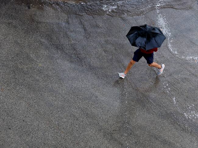 GRAFCVA1137. GODELLA (VALENCIA), 11/06/2024.- Una persona protegida con un paraguas cruza una calle cuando el cielo de la Comunitat Valenciana seguirá hoy nuboso y se esperan chubascos y tormentas ocasionales, que probablemente serán localmente fuertes en el interior y en el tercio sur la segunda mitad del día y no se descarta en el litoral central a primeras horas, según la Agencia Estatal de Meteorología. EFE/Kai Försterling