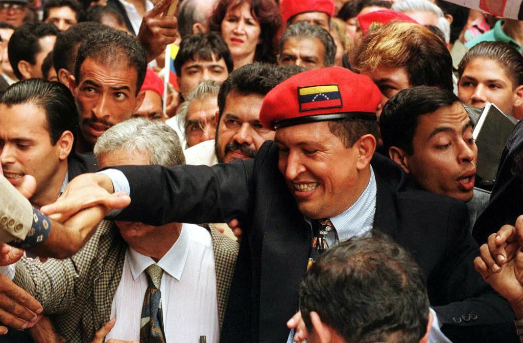 Venezuelan retired Lt. Col. Hugo Chavez Frias (R), who led the 04 February 1992 coup attempt, is greeted by supporters 29 July in Caracas, as he arrives at the Election Council to register his party "Movimiento V Republica" as he starts campaigning for Venezuela's 1998 presidential elections. AFP PHOTO/BERTRAND PARRES        (Photo credit should read BERTRAND PARRES/AFP via Getty Images)
