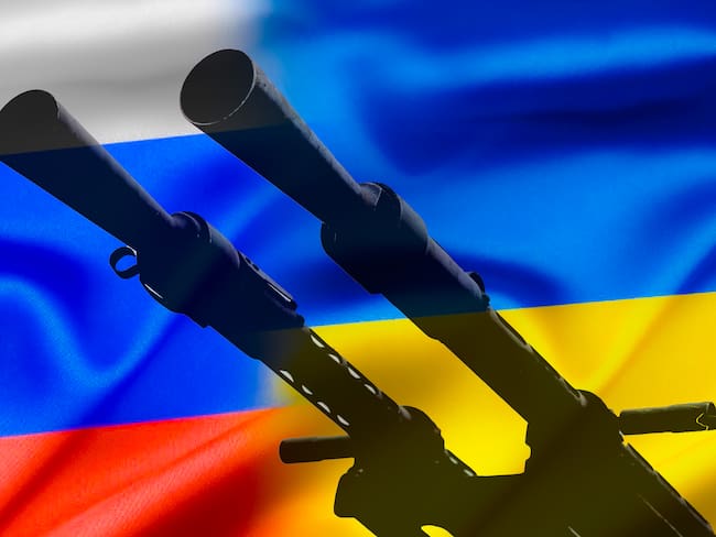 Conflicto militar entre Rusia y Ucrania, un arma contra el fondo de dos banderas estatales de los estados en guerra. Vía Getty Images